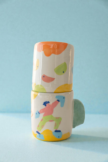 Stack of colorful ceramic cups with simple illustrations on a light blue background